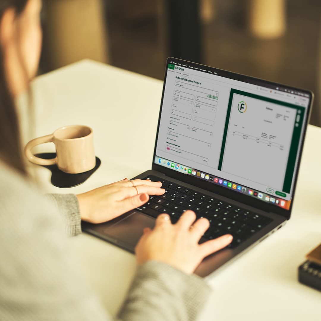Kvinna som arbetar i Fortnox bokföringsprogram, genom att godkänna en automatiskt tolkad faktura.