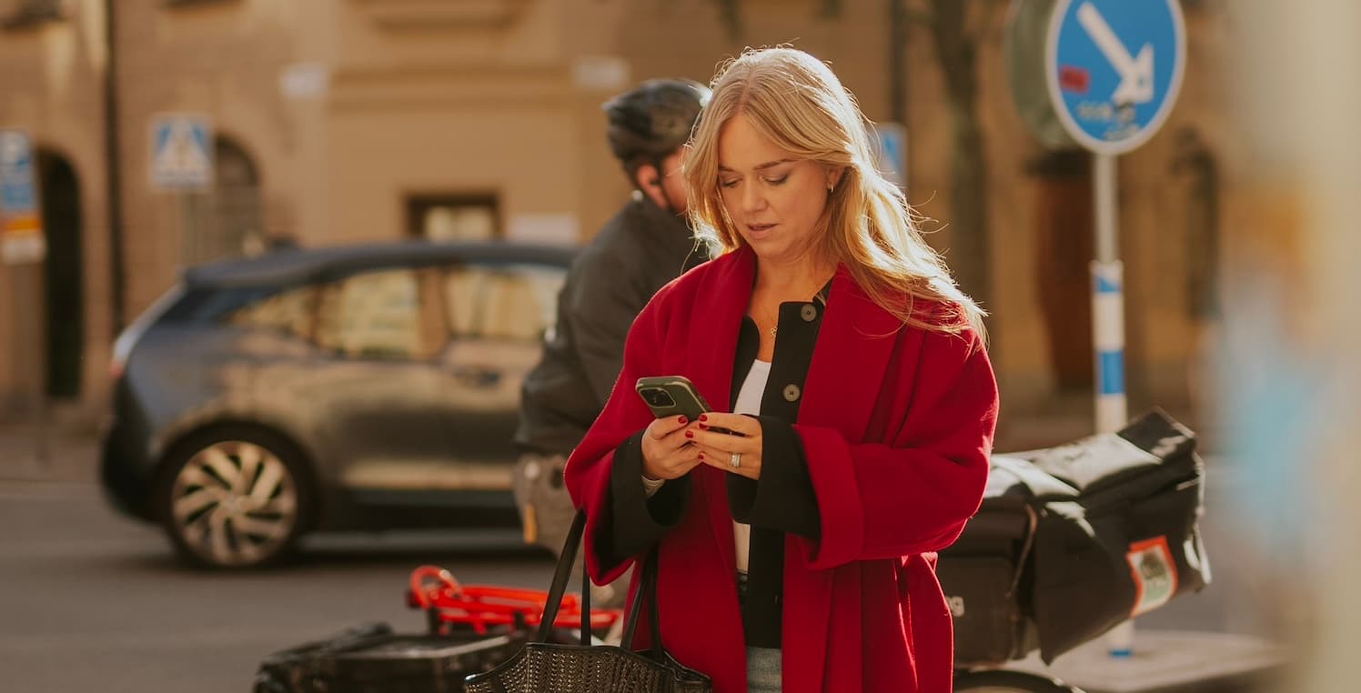 En kvinna står och tittar i en mobiltelefon