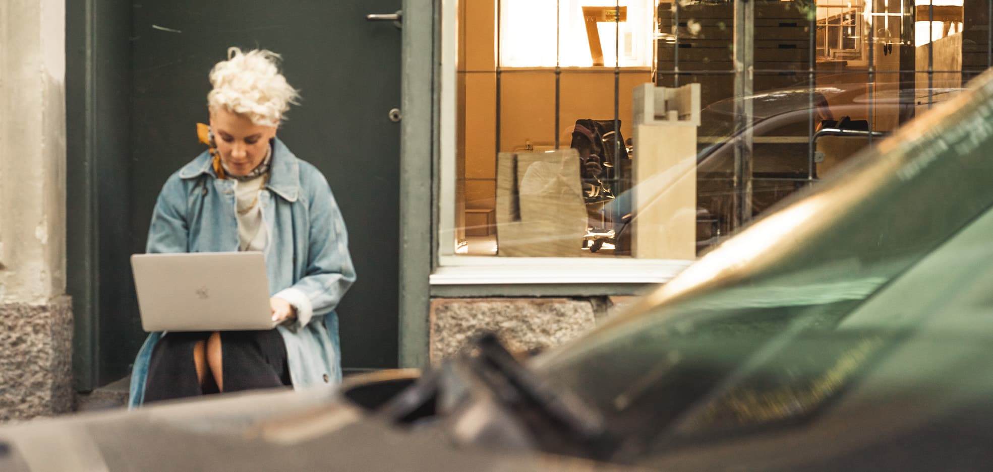 Kvinna sitter utomhus med dator i knä