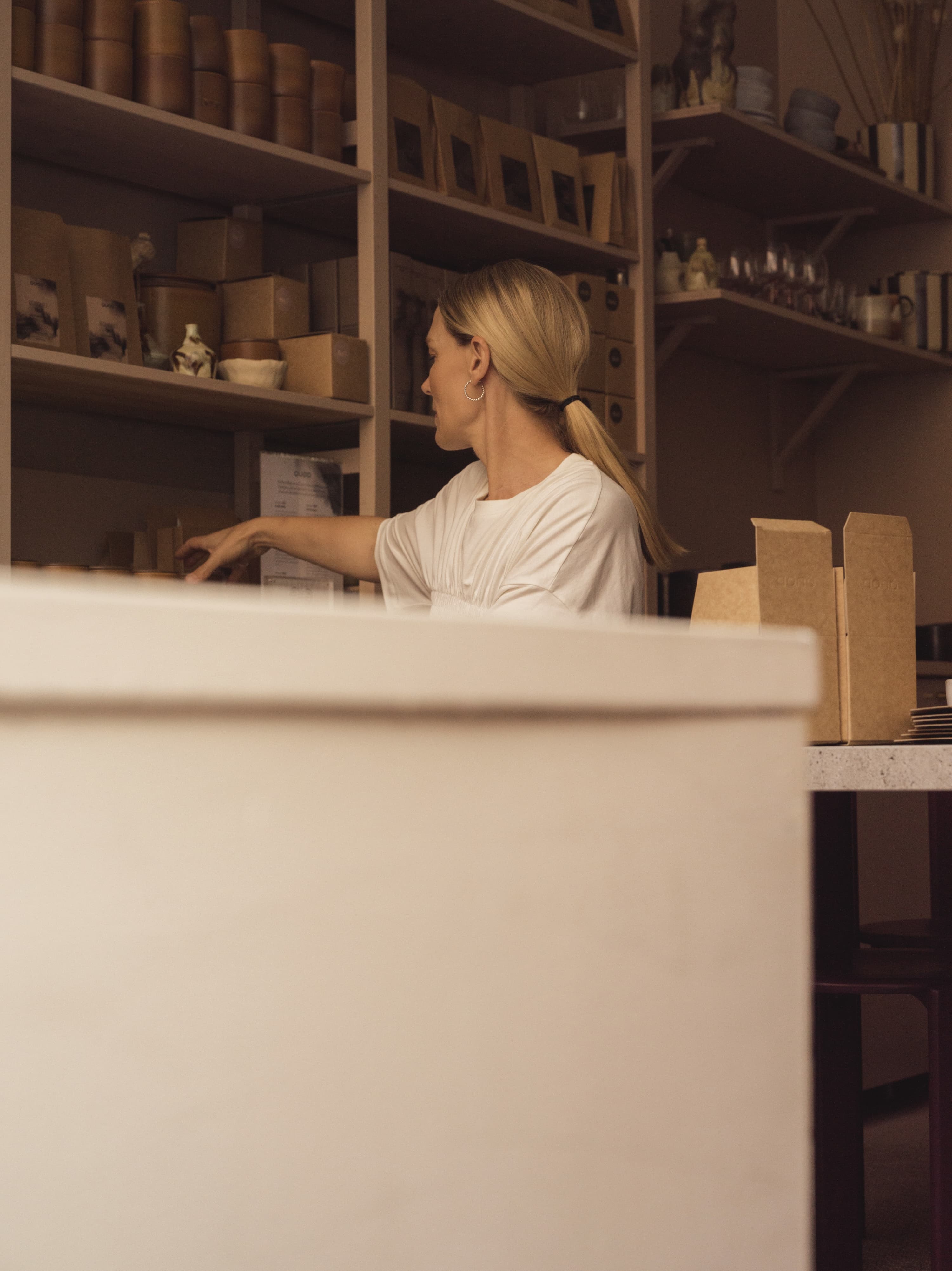 En kvinna som sträcker sig efter något på en hylla